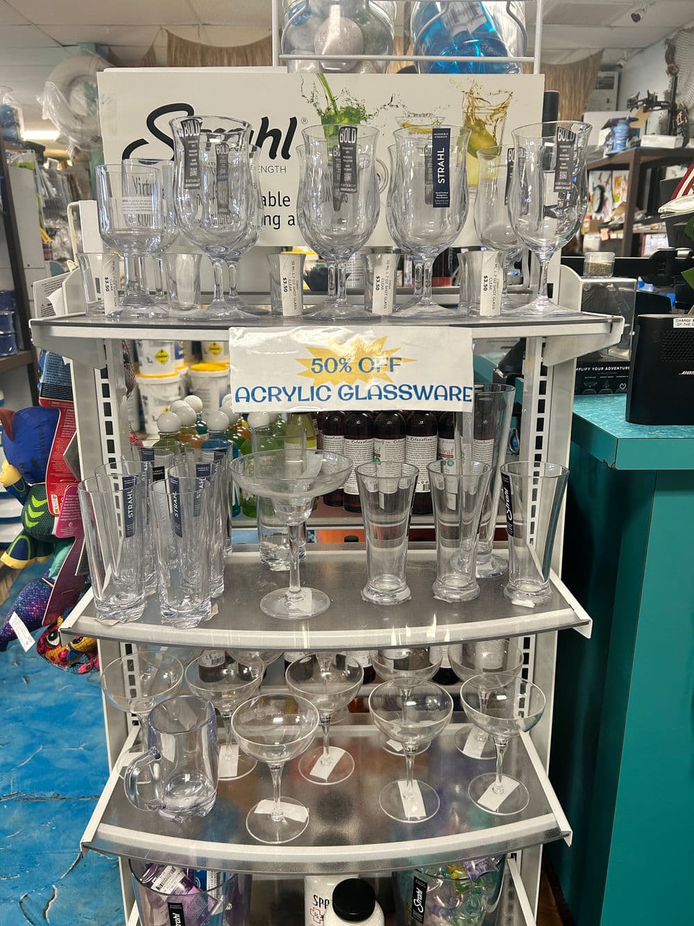 Acrylic glassware display with 50% off sign, featuring various drinkware styles.