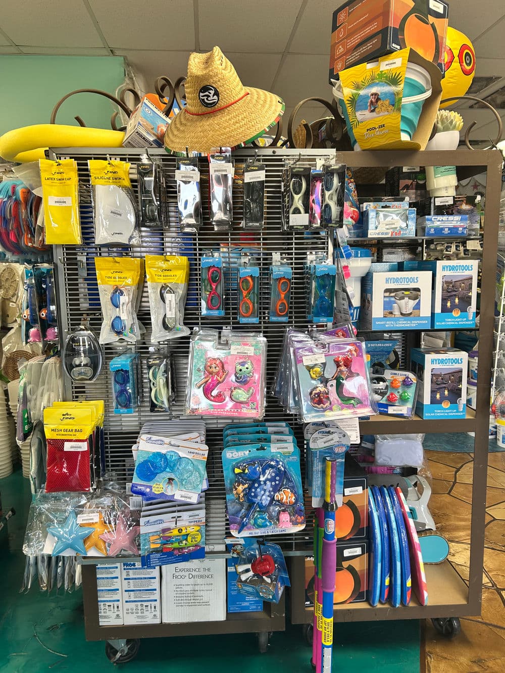 Colorful pool supplies display featuring goggles, floats, and accessories in a retail setting.