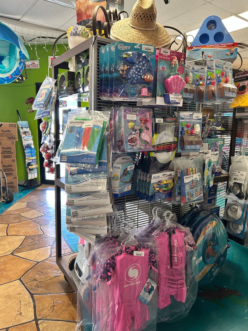 Display of swim gear and accessories in a retail shop, including floaties and life jackets.